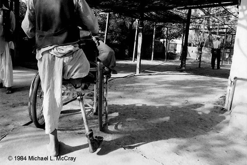 One legged boy pushing a no legged boy in wheel chair